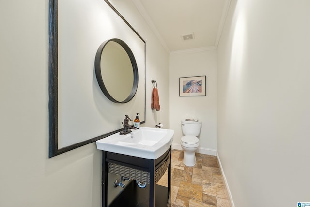 half bathroom featuring crown molding, baseboards, toilet, stone tile flooring, and vanity