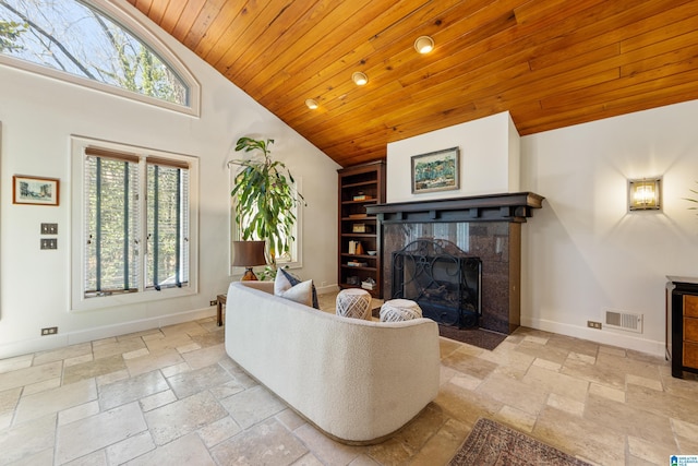 living area featuring visible vents, a fireplace with flush hearth, stone tile floors, wooden ceiling, and baseboards