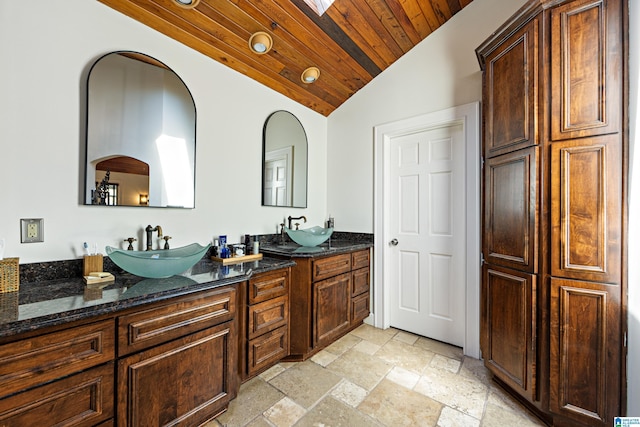 bathroom featuring stone tile floors, vaulted ceiling, wood ceiling, and a sink