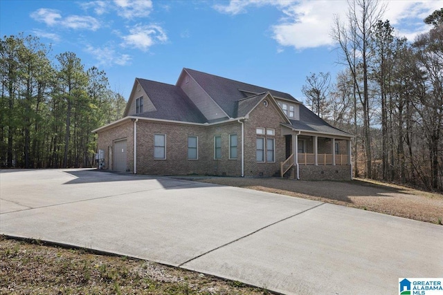 view of front of house featuring concrete driveway, a garage, covered porch, and brick siding