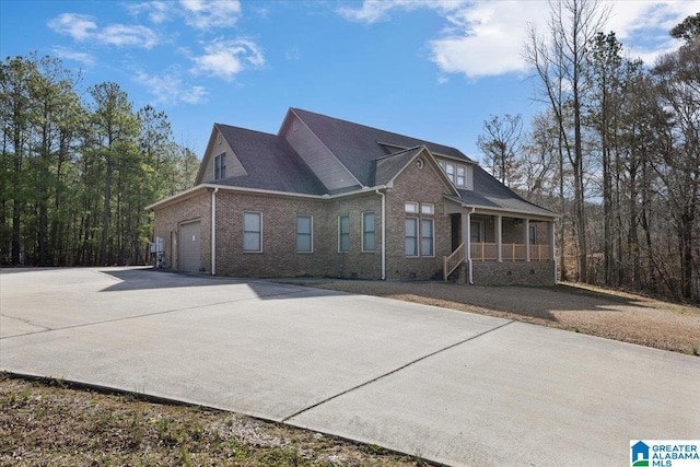 view of front facade featuring brick siding, an attached garage, a porch, and driveway