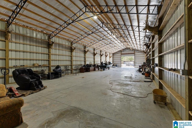 misc room with vaulted ceiling, metal wall, a garage, and concrete flooring