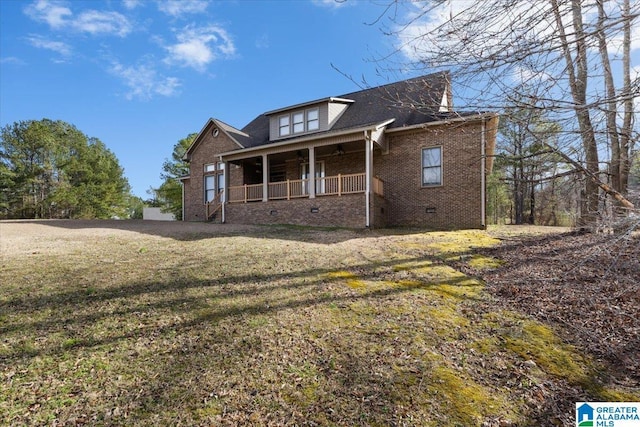 view of home's exterior with a porch, a yard, brick siding, and crawl space