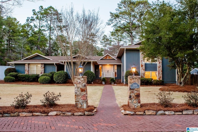 view of front of home with stone siding, decorative driveway, and fence