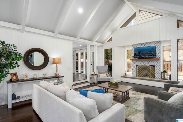 living area featuring a fireplace, beamed ceiling, wood finished floors, and a wealth of natural light