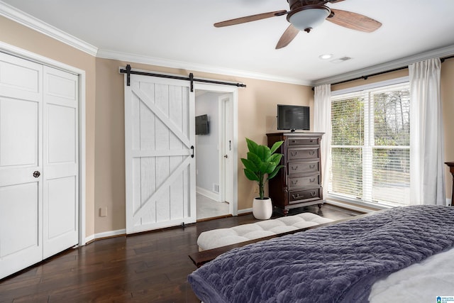 bedroom with a barn door, crown molding, wood finished floors, and visible vents