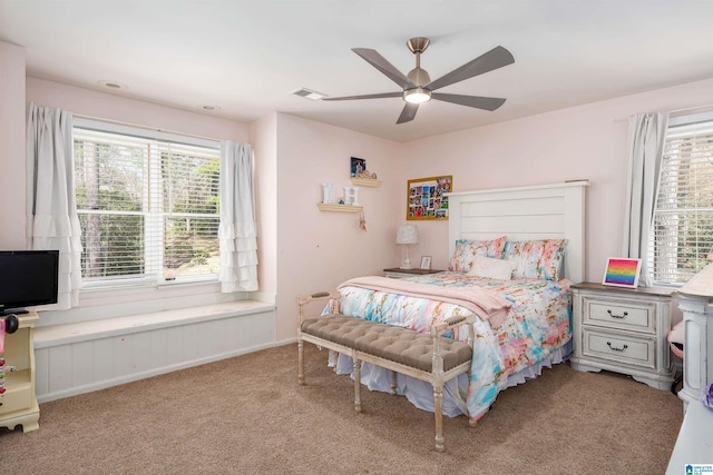 bedroom featuring visible vents, multiple windows, light colored carpet, and a ceiling fan