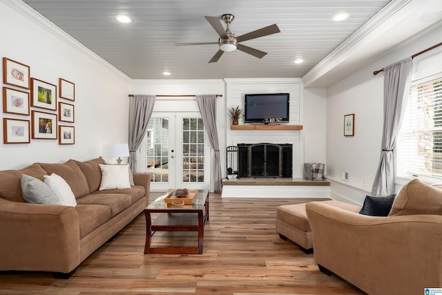 living area with a ceiling fan, light wood finished floors, a fireplace, recessed lighting, and ornamental molding