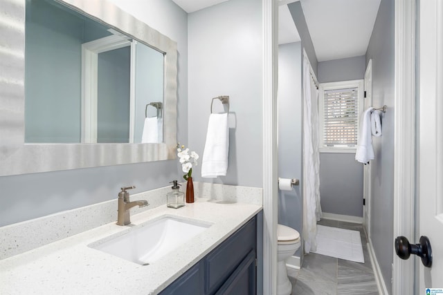 full bathroom featuring toilet, vanity, and baseboards