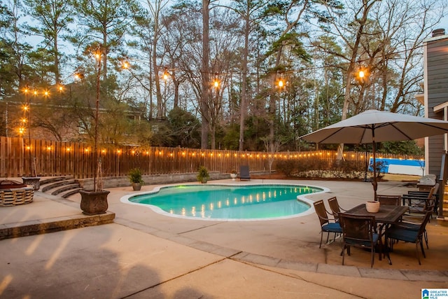 pool at dusk with a patio area, a fenced in pool, and a fenced backyard