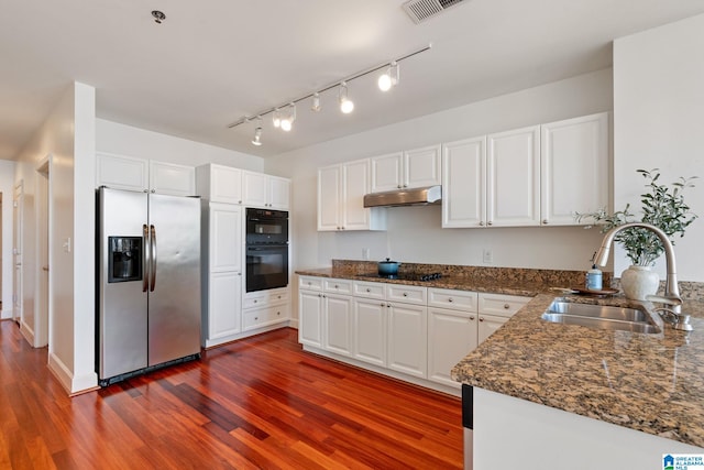 kitchen featuring black appliances, a sink, under cabinet range hood, white cabinetry, and dark wood-style flooring