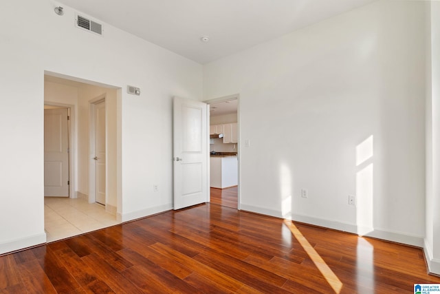 unfurnished room with visible vents, baseboards, and wood finished floors