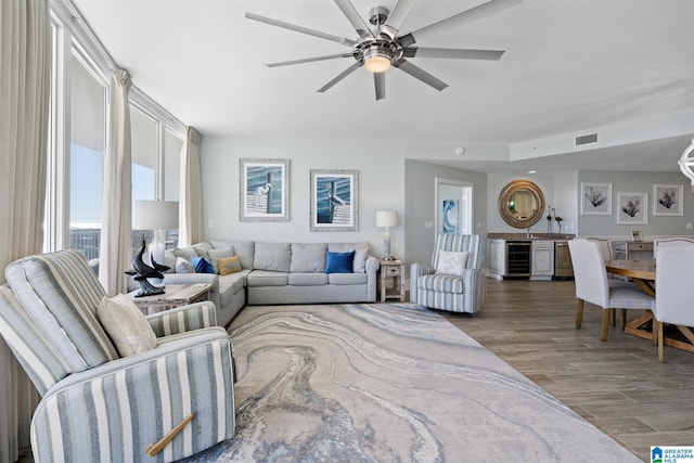 living area with a ceiling fan, wine cooler, wood finished floors, and visible vents