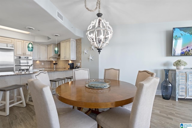 dining space featuring a chandelier, visible vents, and light wood-style flooring