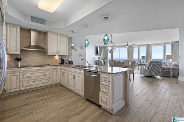 kitchen with light wood-type flooring, a sink, tasteful backsplash, stainless steel dishwasher, and wall chimney range hood