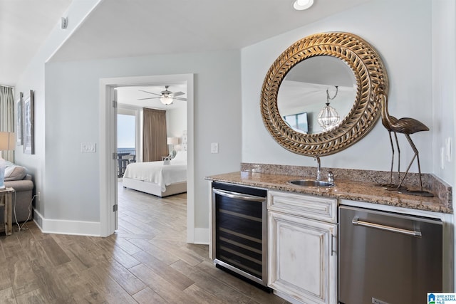 interior space featuring beverage cooler, wet bar, a sink, dark wood-type flooring, and stainless steel dishwasher