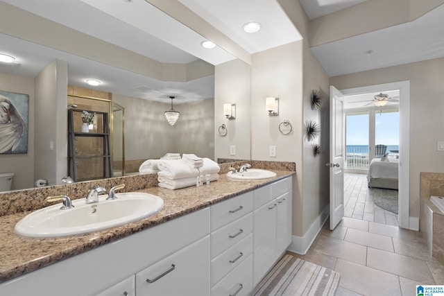 bathroom with double vanity, a shower stall, a ceiling fan, and a sink