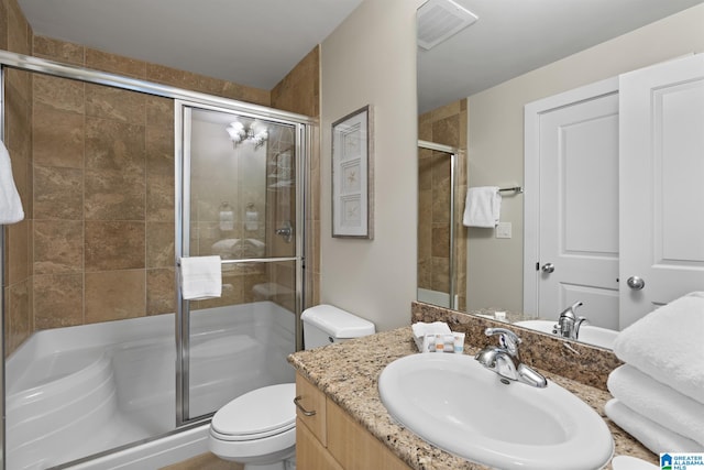 full bath featuring vanity, a shower stall, toilet, and visible vents