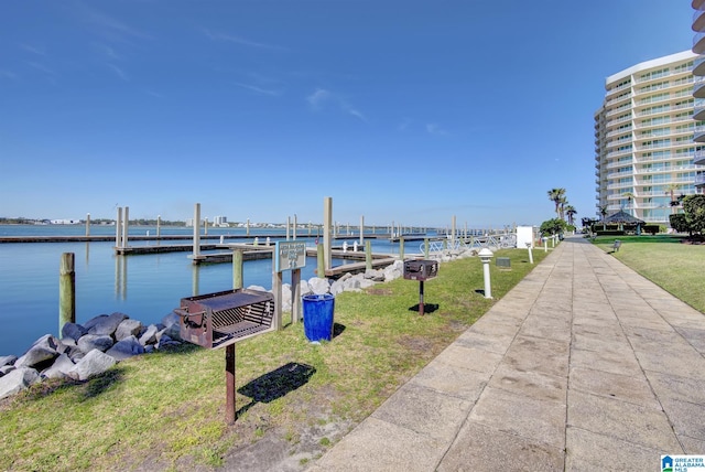 view of dock with a lawn and a water view