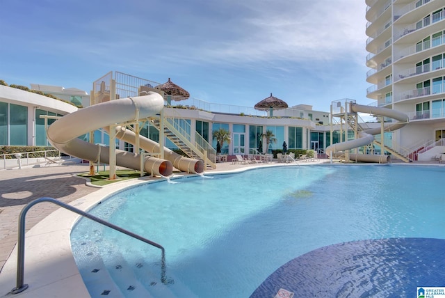 community pool featuring a water slide and a patio area