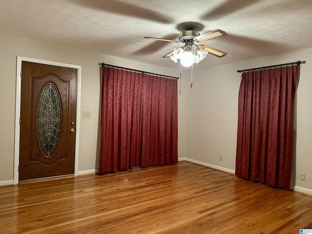 foyer with a textured ceiling, a ceiling fan, baseboards, and wood finished floors