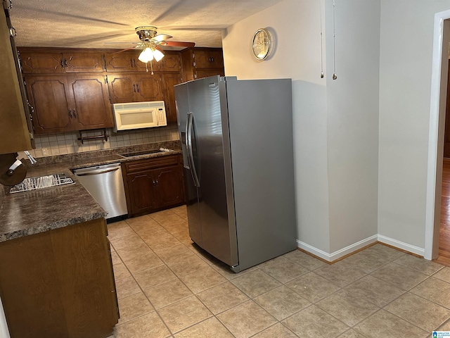 kitchen with light tile patterned floors, a ceiling fan, decorative backsplash, appliances with stainless steel finishes, and dark countertops