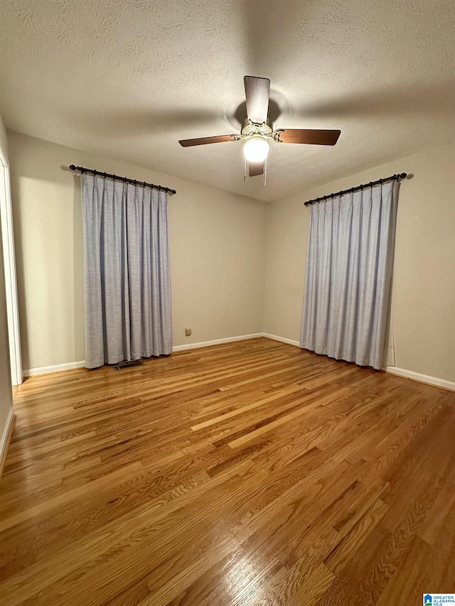 unfurnished room with wood finished floors, baseboards, and a textured ceiling