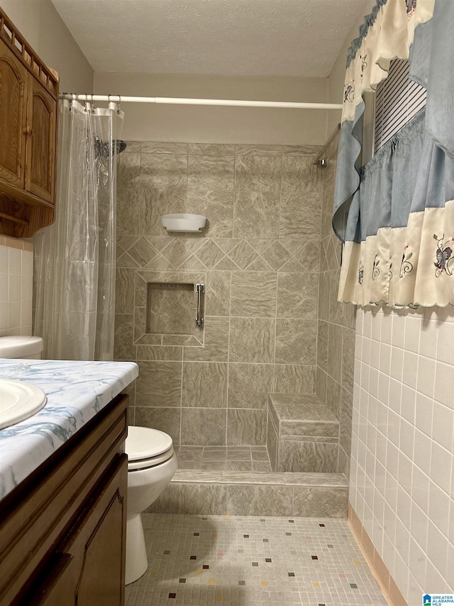 bathroom with vanity, toilet, and tiled shower