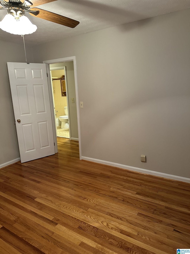 unfurnished room featuring baseboards, a textured ceiling, wood finished floors, and a ceiling fan