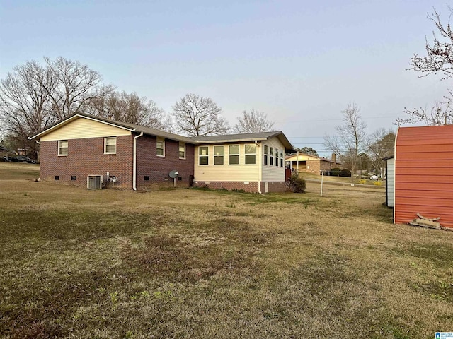 rear view of house with crawl space, a yard, brick siding, and central AC unit