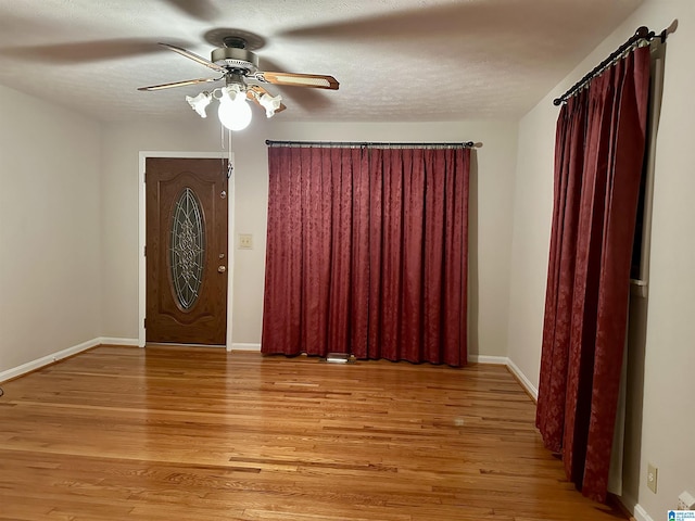 entrance foyer with a ceiling fan, baseboards, light wood-type flooring, and a textured ceiling