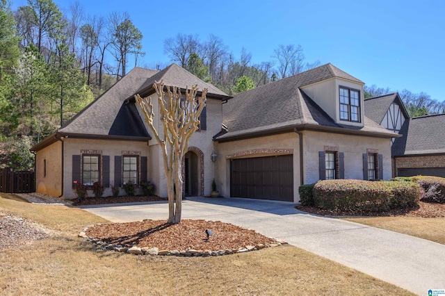 view of front facade featuring driveway, fence, roof with shingles, an attached garage, and brick siding