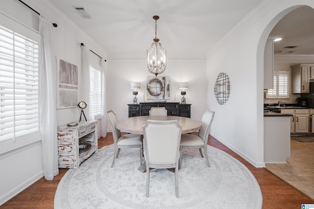 dining room with visible vents, arched walkways, an inviting chandelier, and crown molding