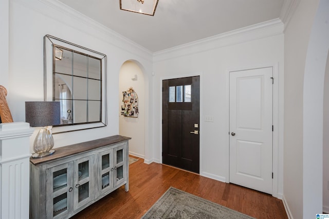 entryway featuring dark wood-type flooring, crown molding, arched walkways, and baseboards