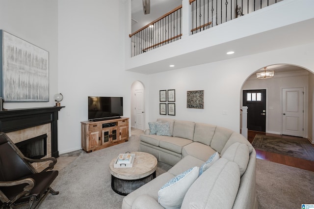 living area with arched walkways, recessed lighting, a tile fireplace, and baseboards