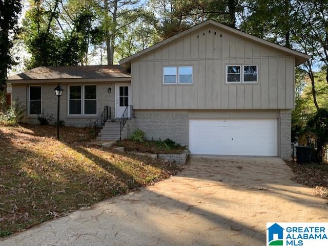 split level home with brick siding, a garage, and driveway