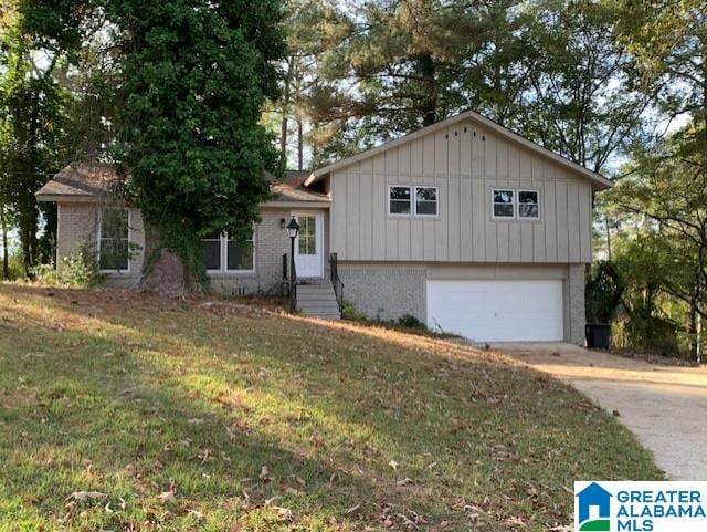 tri-level home with a front lawn, an attached garage, brick siding, and driveway