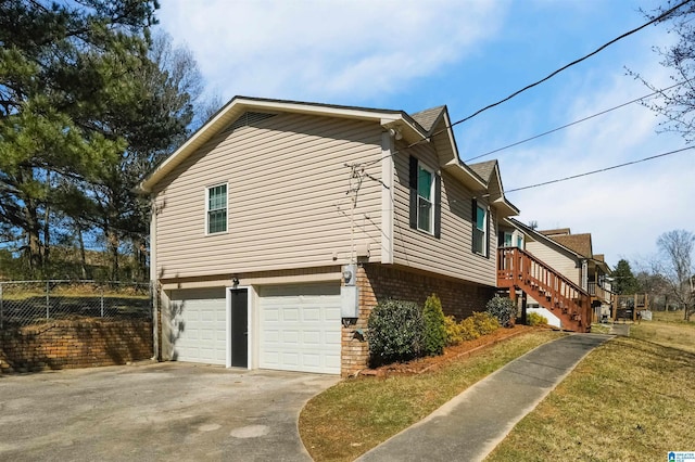 view of home's exterior featuring brick siding, fence, stairway, driveway, and an attached garage