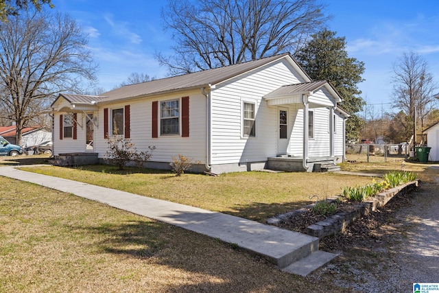 view of front facade with metal roof, a front lawn, and fence