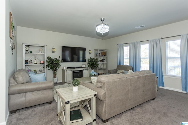 living room with light carpet, visible vents, baseboards, and a glass covered fireplace