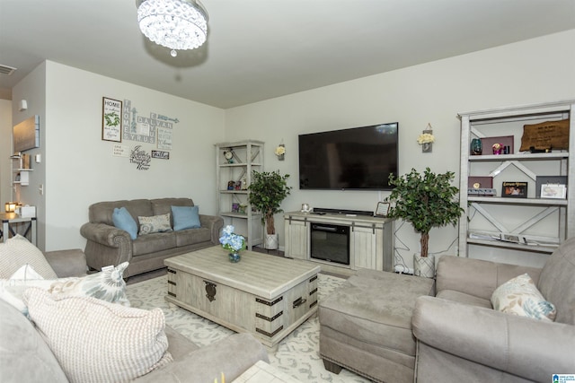 living area featuring a glass covered fireplace, a notable chandelier, and visible vents