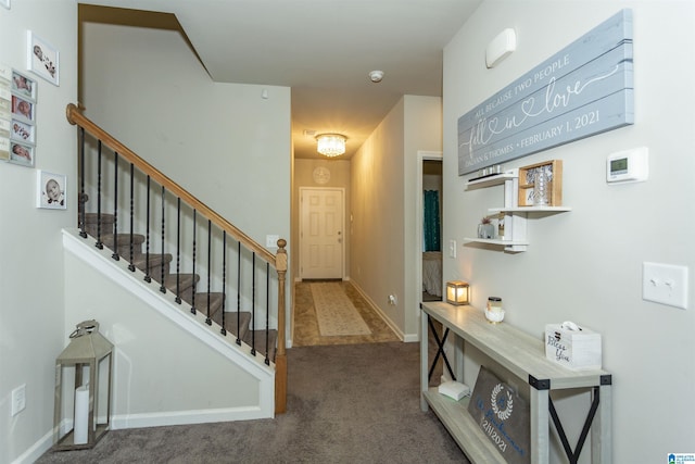 foyer entrance featuring stairway, baseboards, and carpet