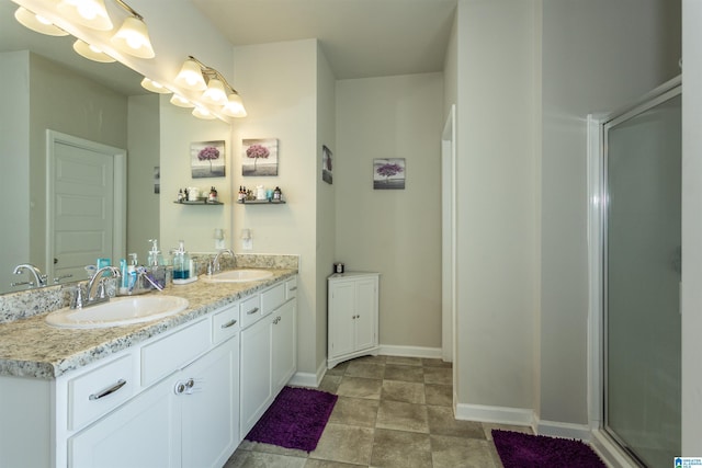 bathroom with double vanity, an enclosed shower, baseboards, and a sink