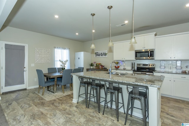 kitchen featuring visible vents, backsplash, a breakfast bar, stainless steel appliances, and a sink