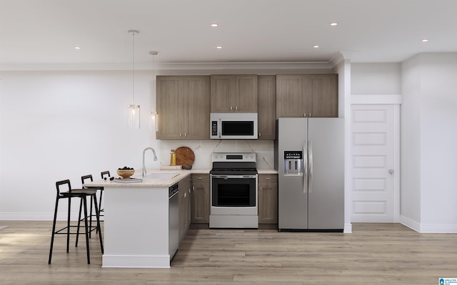 kitchen featuring light wood finished floors, light countertops, appliances with stainless steel finishes, a peninsula, and a sink