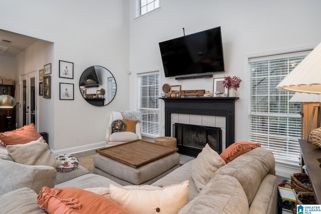 living area with a tiled fireplace, a high ceiling, wood finished floors, and baseboards