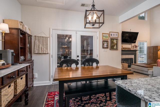 dining space featuring visible vents, a notable chandelier, a tiled fireplace, dark wood finished floors, and baseboards