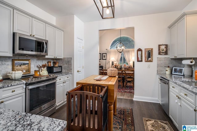 kitchen featuring light stone counters, appliances with stainless steel finishes, and dark wood-style flooring