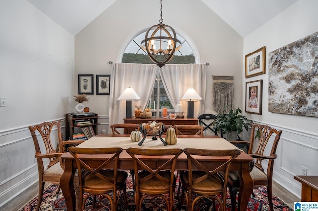 dining room with a wainscoted wall, wood finished floors, a chandelier, and vaulted ceiling