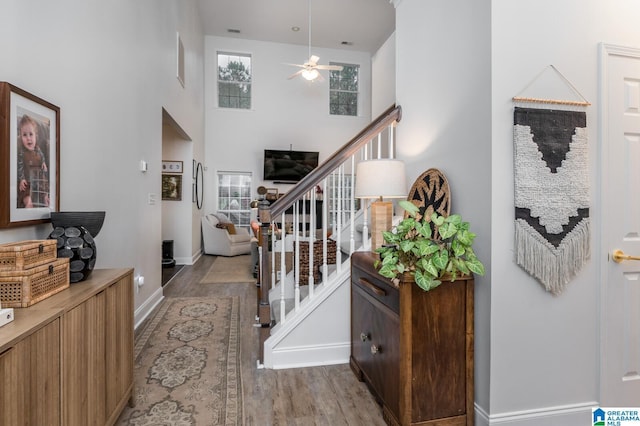 interior space with stairs, plenty of natural light, wood finished floors, and ceiling fan